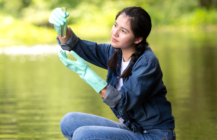 Woman at lake holding water sample