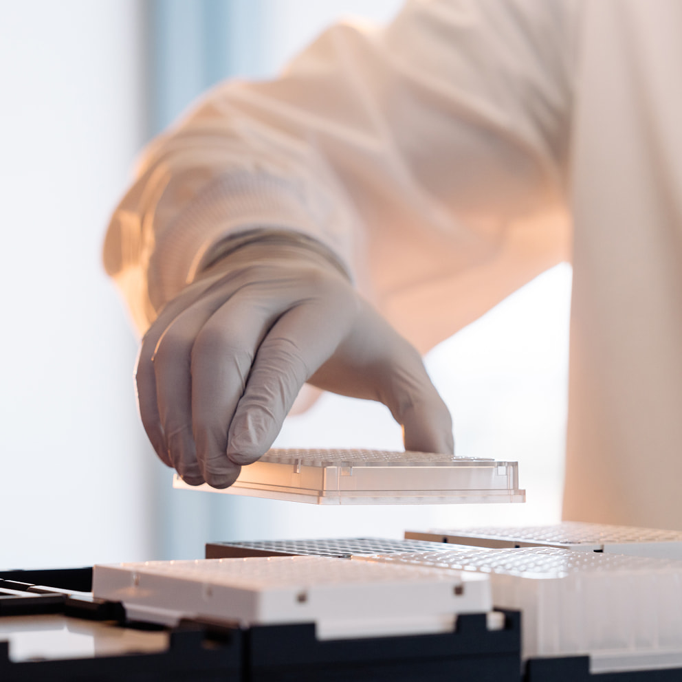 Close up image of a scientist placing a plate on a carrier of a Hamilton ML Star